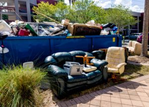 A residential garbage dump area with chairs and appliances.