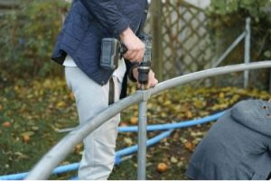 A man holding a tools to disassemble a trampoline
